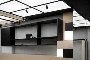 An office reception area featuring modern design elements such as black metal shelves, concrete walls, a blending cube instal