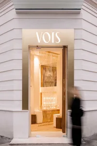 A modern retail storefront with glass and rope elements, featuring warm lighting inside.