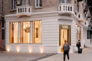 A modern retail storefront with a white stone exterior, illuminated by warm indoor lighting.