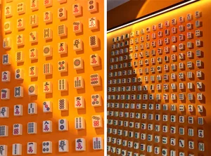 A wall adorned with patterned ceramic tiles featuring symbols and characters associated with the game of Mahjong.