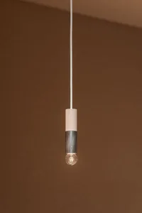 A minimalist light fixture featuring a metal cylinder with a single bulb.