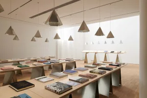 A modern library with wooden tables, metal shelves, and paper books displayed on the shelves.