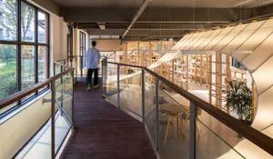 A modern library interior with wooden shelves and tables.