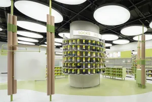 A well-lit, modern retail shop displaying various products on a round shelving unit with a sign labeled 'Socks'.