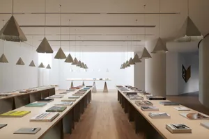 A modern industrial library with hanging lights and books arranged on tables.