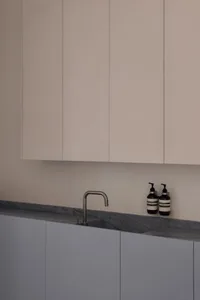 Modern kitchen with minimalist design featuring concrete countertops and cabinets.