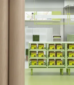 A minimalist retail store with green and yellow shelving units displaying products.