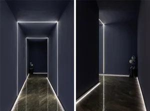 Modern corridor with concrete walls and floor, illuminated by concealed linear lighting.