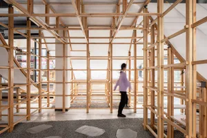 A modern interior design featuring a wooden frame structure with a person walking through it.