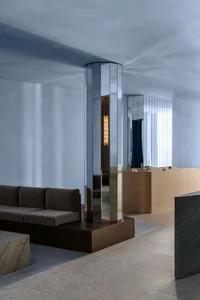A modern lobby space featuring mirrored columns and leather seating.