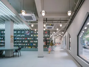 寬敞的現代圖書館室內，混凝土牆面、燈罩與書架。
