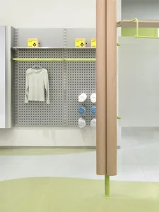 Modern retail store display featuring a shelf with a grey pegboard, yellow boxes, and rolled towels.