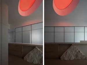 Modern hotel lobby with glass partitions and marble walls illuminated by orange circular lights.