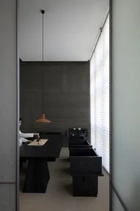 Minimalist-designed living room featuring a dark wooden tea table and glass tea set, with a tea ceremony in progress.