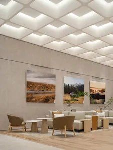 A modern lounge space featuring concrete walls, wooden furniture, and fabric cushions.
