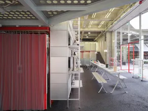Industrial office kitchen with metallic shelves, glass countertops, and concrete flooring.
