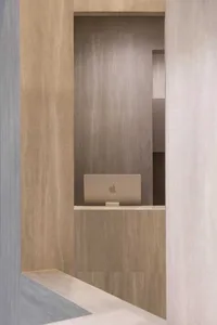 A minimalist office workspace made of marble with a laptop on a shelf.