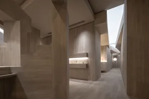 A modern corridor with a concrete wall and floor, featuring a display of bottles and a light fixture.