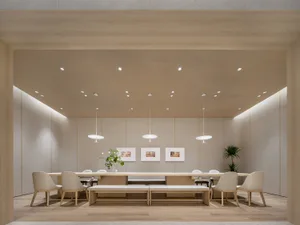 Modern meeting room with wooden tables, chairs, and benches, featuring minimalist design and natural lighting.