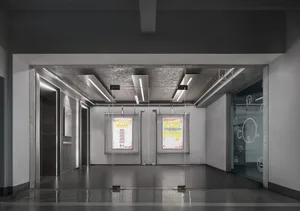 A modern office lobby with a concrete floor and walls, featuring glass doors and windows.