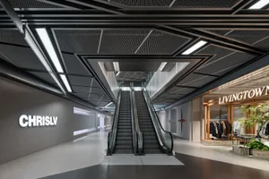 A modern shopping mall interior with metallic, glass, and concrete materials.