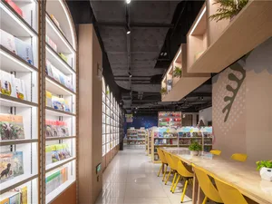 Modern library interior with illuminated floating shelves and a long wooden table with yellow chairs.