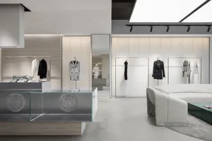 A minimalist retail store with glass, concrete, and metal materials showcasing fashion retail displays.
