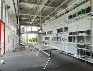 A modern commercial space featuring metal and glass shelving units and tables.