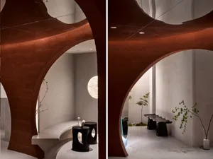 A minimalist interior space with modern concrete walls, a curved design, and a geometric lighting fixture