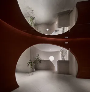 A modern interior space with red curved walls and concrete materials.