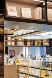 A well-lit library interior featuring modern wood shelves filled with books.