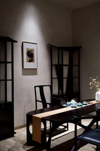 Modern living room with a wooden tea table and matching chairs, featuring a minimalist tea set.