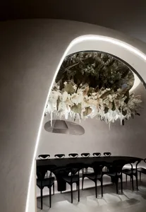 A minimalist restaurant interior featuring a large, intricate floral installation made of dried flowers and plants.