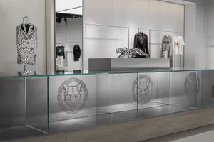 服飾店展示區，玻璃櫃台上擺放金屬豹雕像，衣架上陳列服裝