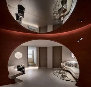 A modern living room with a concrete floor, curved walls, and minimalist furniture.
