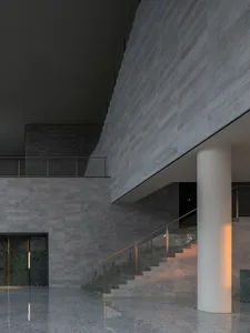 Modern, minimalist design featuring a marble staircase with a white cylindrical column, illuminated by warm lighting within a