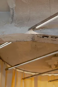 Exposed concrete ceiling with metal pipes and conduits.
