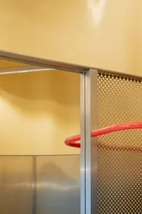 A red and metallic railing with a perforated metal panel in an industrial setting.