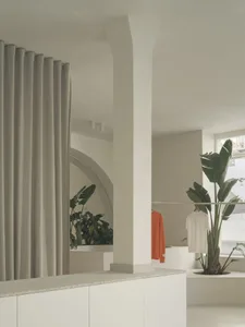 A minimalist clothing shop with concrete walls and large windows displaying fashion items.