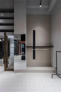 A minimalist modern industrial interior space featuring concrete walls and floors with dark metal accents.