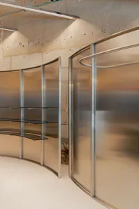 A modern interior space featuring glass walls and shelves.