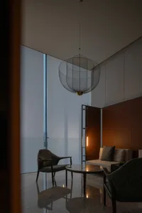 Modern living room with a glass panel window, minimalist furniture, and contemporary lighting.