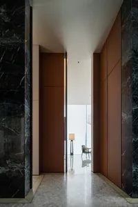 A modern interior corridor featuring marble walls, concrete flooring, and industrial-style lighting.