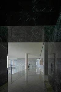 A person standing in a modern marble hallway.