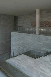 Modern interior space with marble floors, walls, and stairs, featuring a glass railing and polished surfaces.