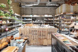 工藝店室內，木質層架、金屬懸掛工具、玻璃器皿與塑膠配件。