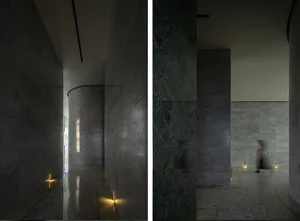 Interior space with dark marble walls and floors, featuring subtle lighting.