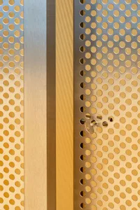 A metallic door with perforated pattern and a key lock mechanism, showcasing industrial design elements.