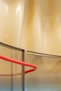 A modern industrial staircase with a red handrail, made of metal.