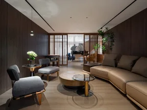 A modern living room with wooden walls, a beige leather sofa, and circular glass-top tables.